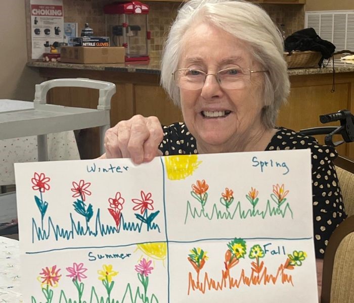 older woman showing drawing of flowers for each season of the year